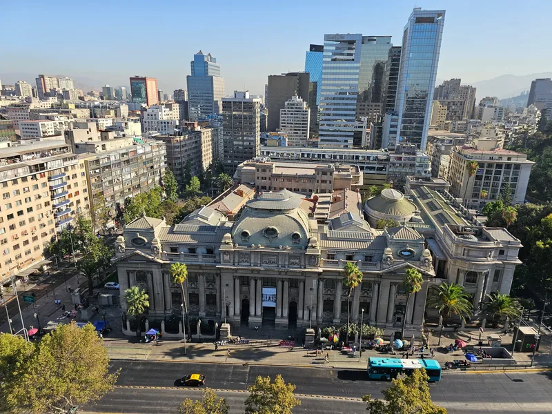 Centro de Santiago, com um edifício clássico de colunas em primeiro plano e prédios ao fundo.