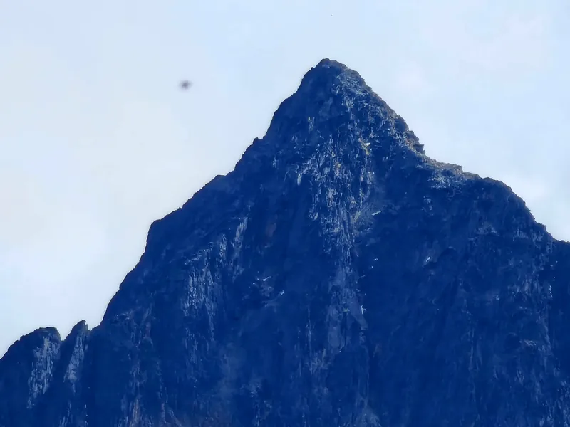Pico rochoso de montanha, em tons de azul, sob o céu, na Terra do Fogo.