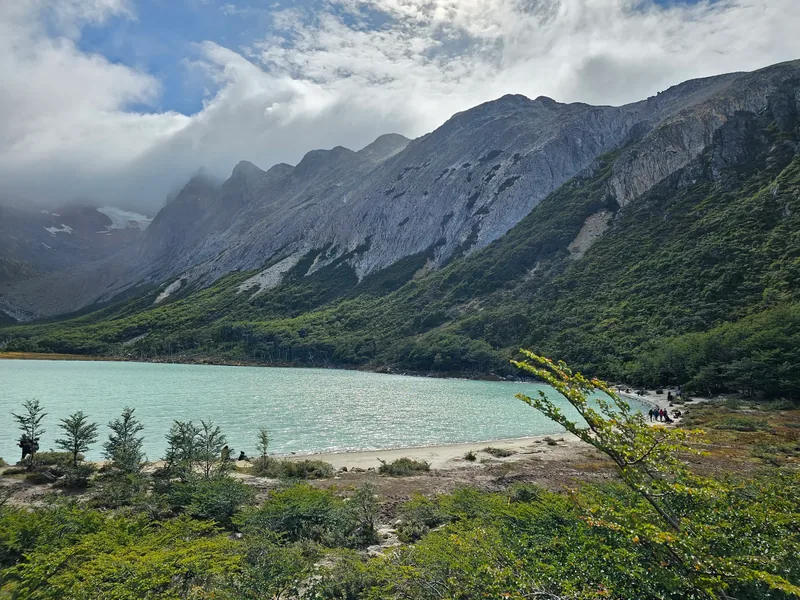Lago de água turquesa, com montanhas ao fundo.