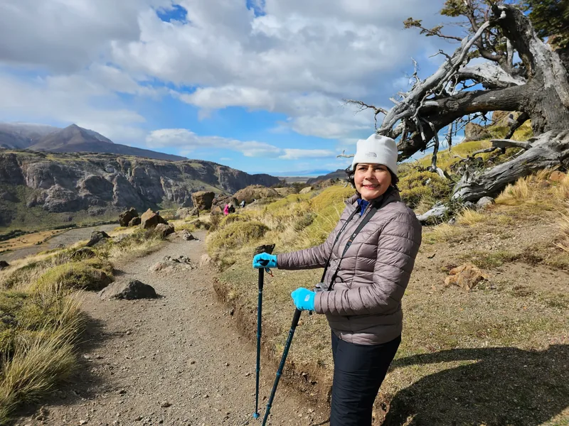 Denise em uma trilha em El Chaltén, com montanhas ao fundo.