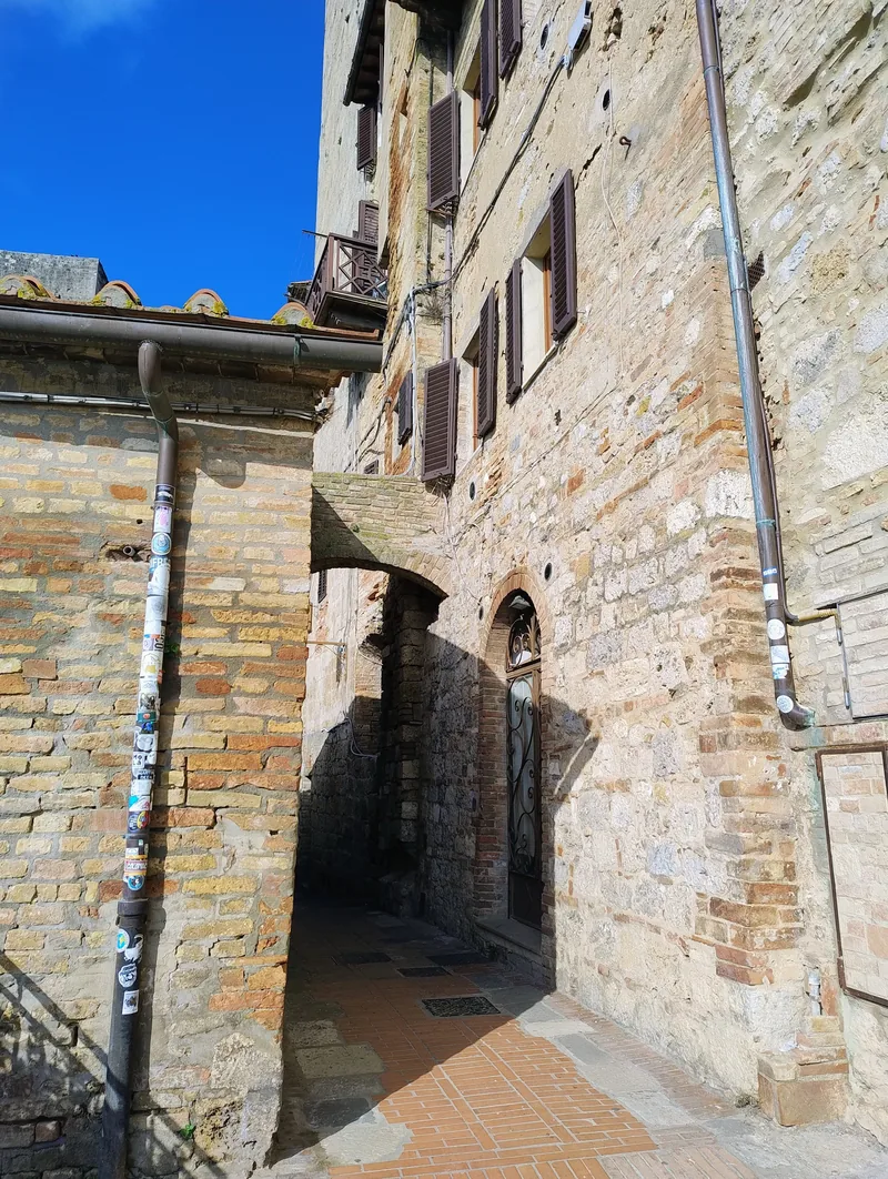 Passagem em arco de pedra levando a uma rua histórica.